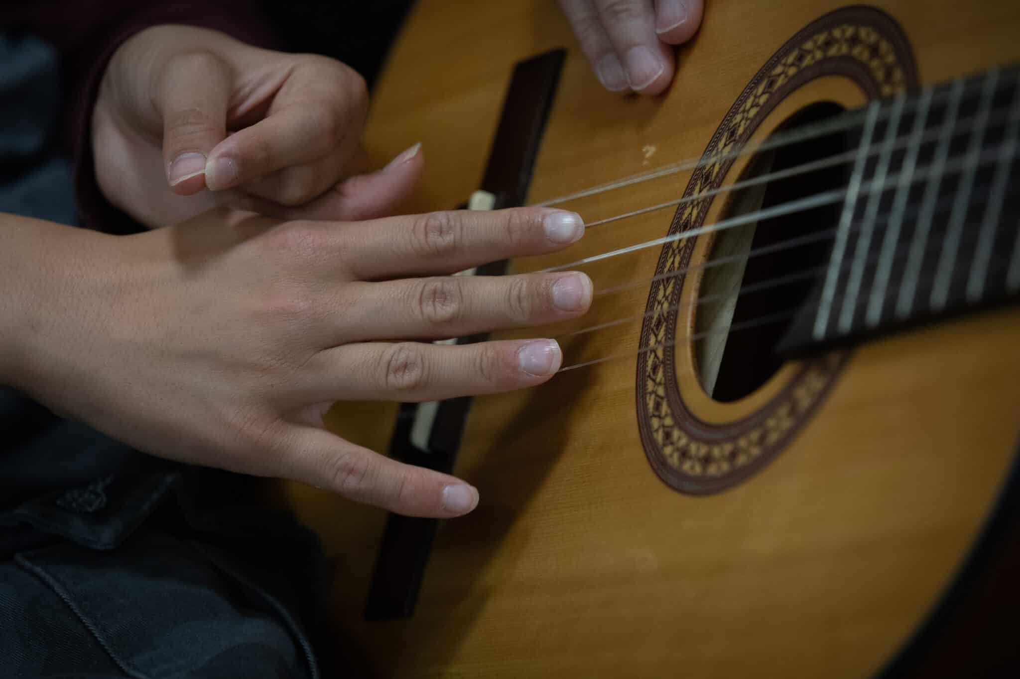 Hender som fører hender over gitarstrenger